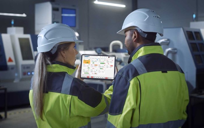 Dos operarios sosteniendo un tablet con un sistema MES en pantalla